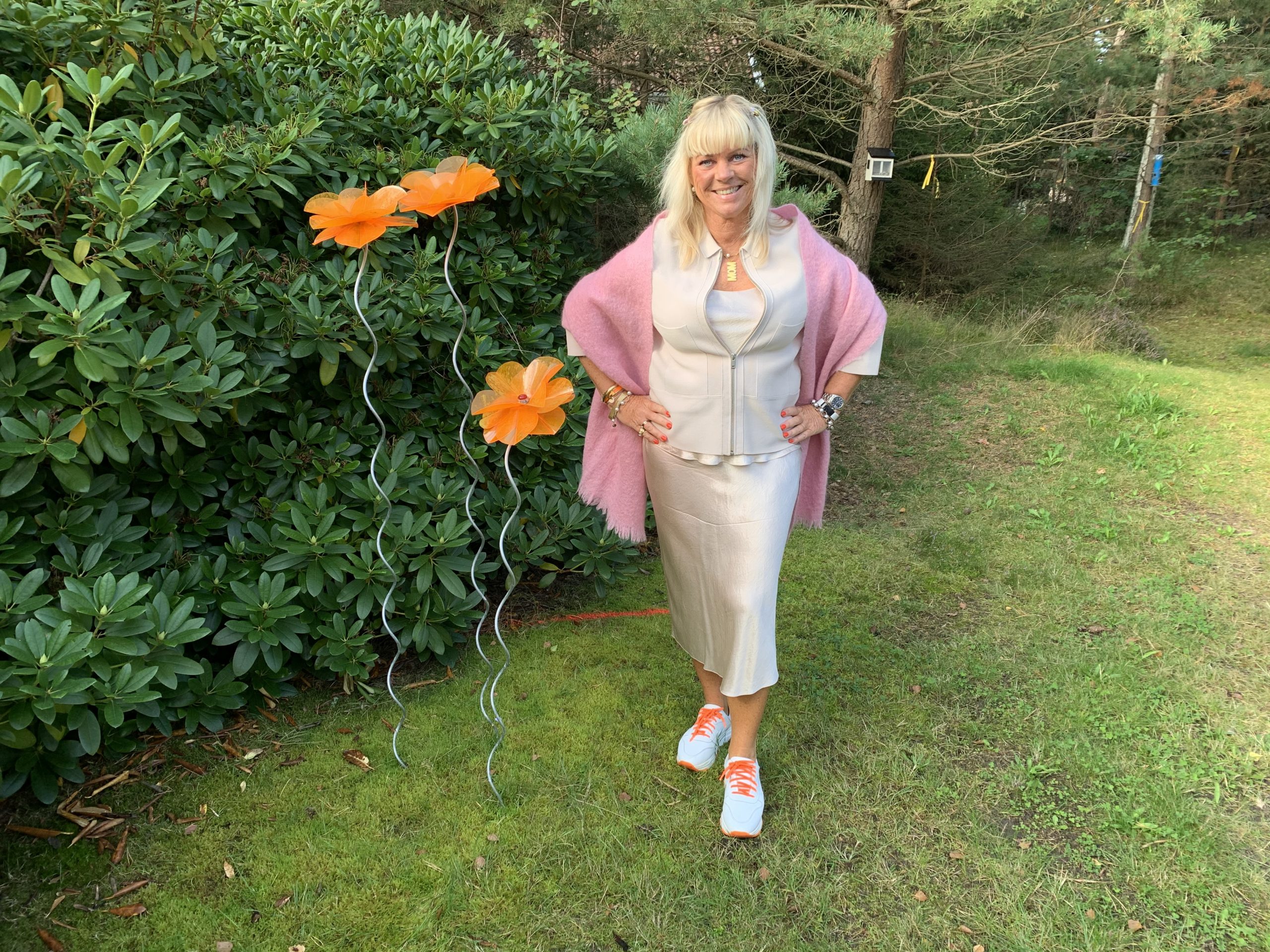 I rosa outfit framför blommorna från Margareta Forslund 